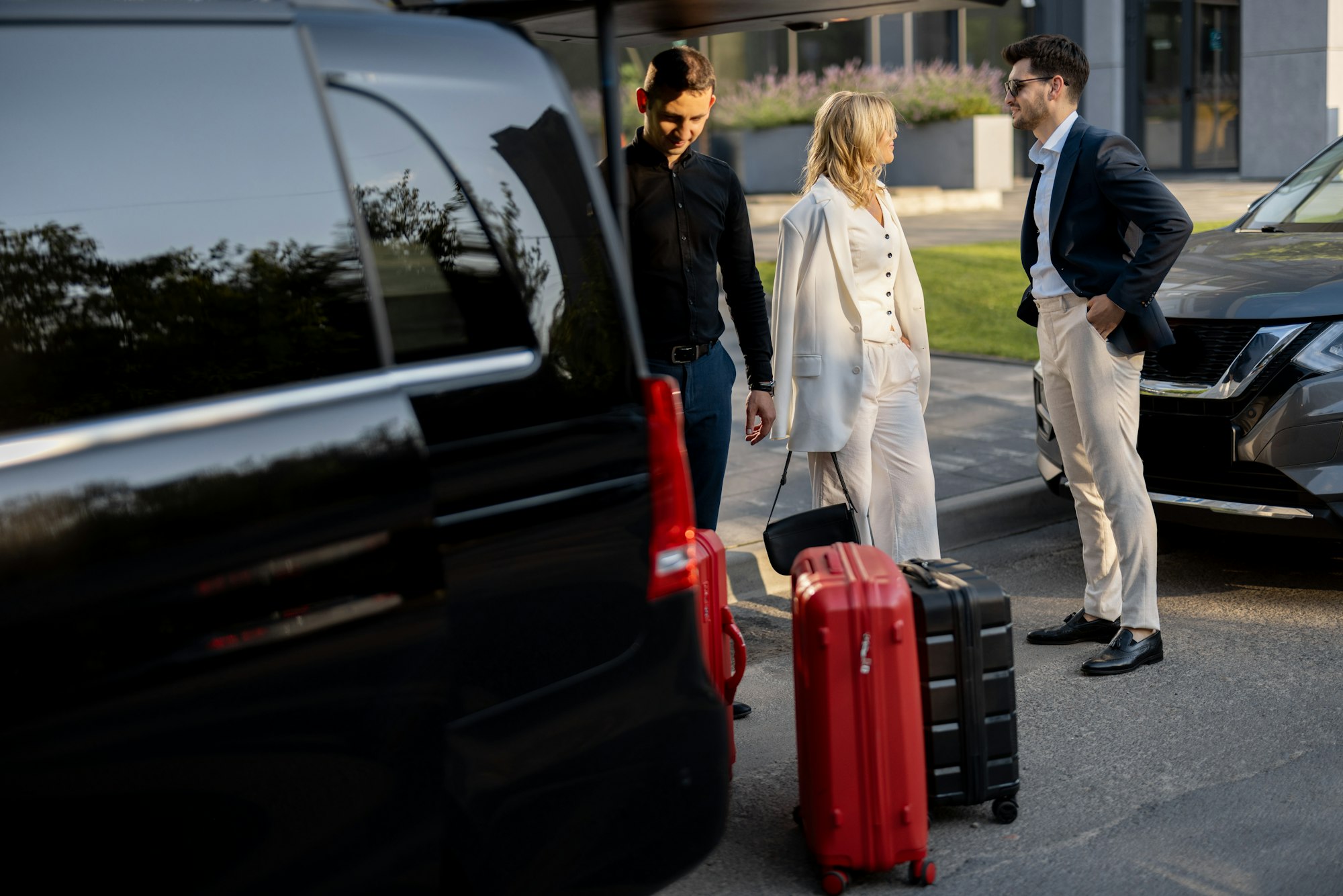 Business couple near minivan taxi with a suitcases and chauffeur